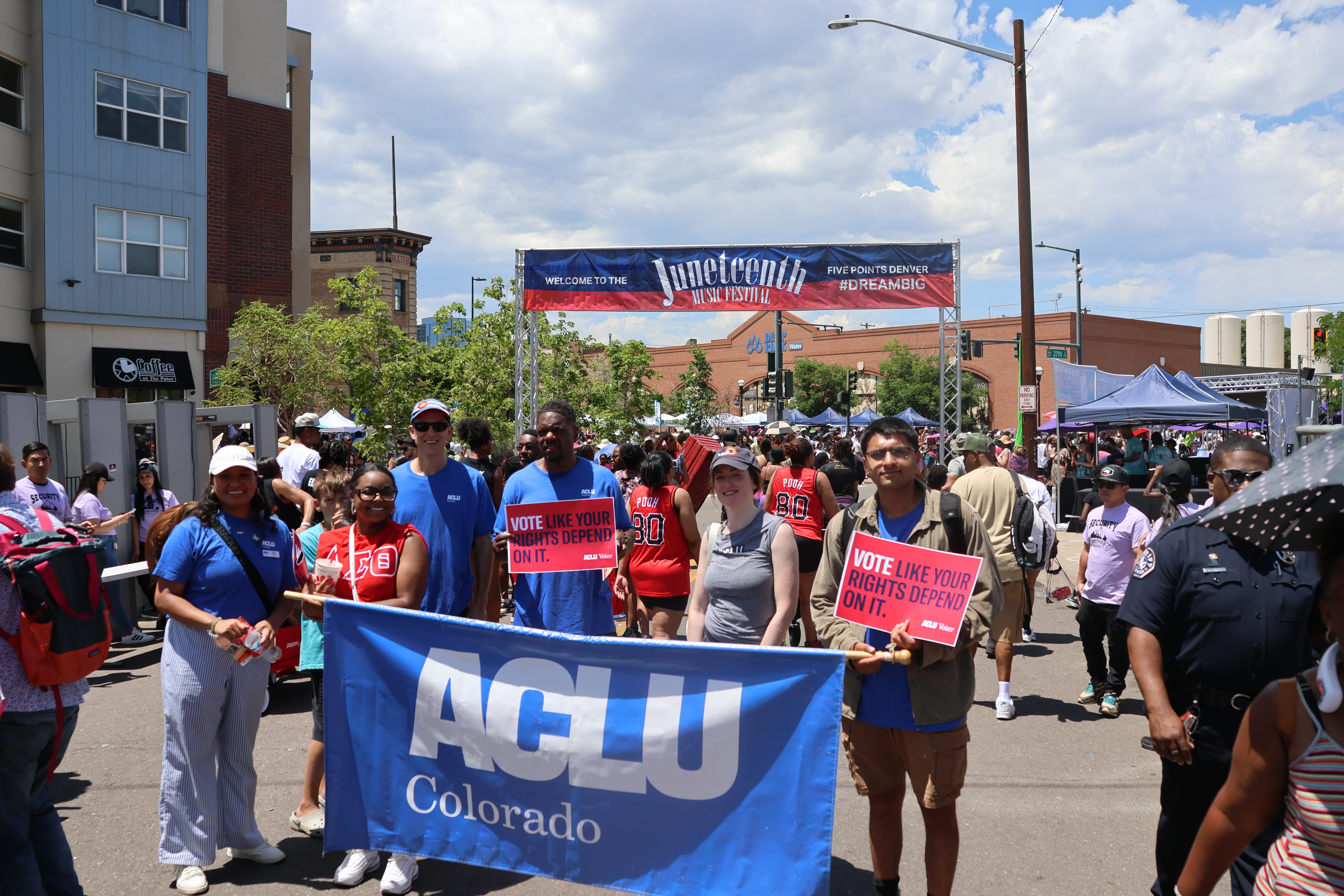 Photo of people in a parade holding a banner that says ACLU Colorado in front of a larger banner that says Juneteenth