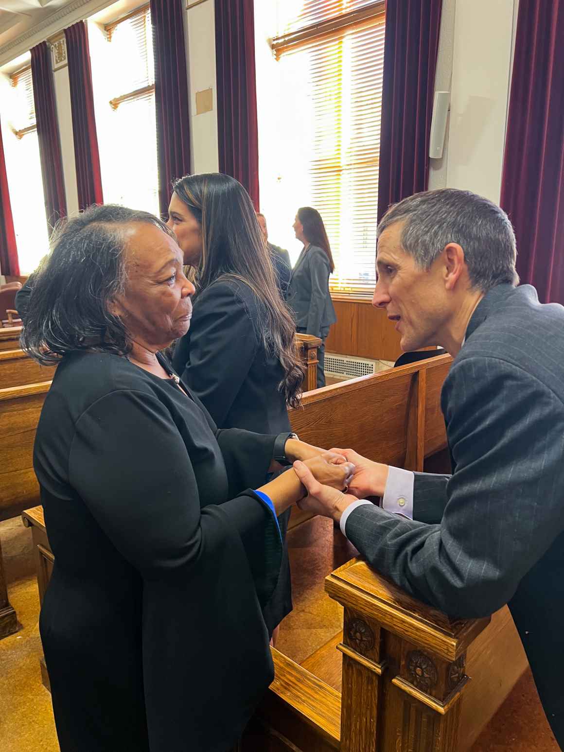 Photo of Ruby Johnson and ACLU of Colorado legal director Tim MacDonald shaking hands in a Denver courtroom